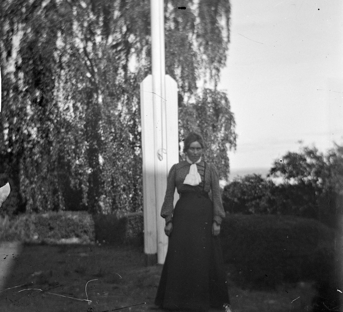 Anna Benjamine Hoel (født 30/3-1872) ved flaggstangen på Hovinsholm gård, Helgøya i Ringsaker. Foto Jacob Hoel. 