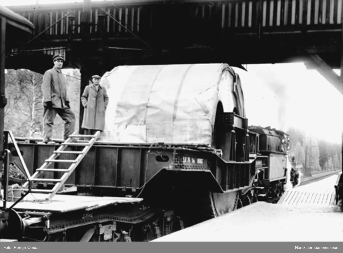 Et damplokomotiv av type 18a foran Rjukanbanens dyplastevogn, lastet med en 60 tonns stålsylinder til Mesna Tresliperi & Kartonfabrik