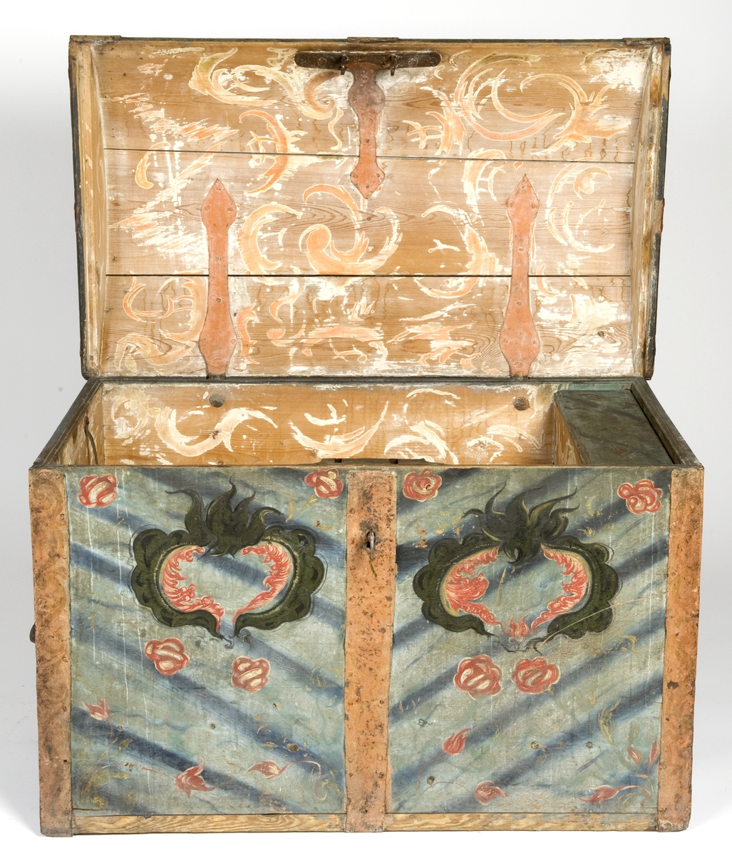 Kiste med buet lokk og smijernsbeslag og bånd. Rosemalt lokk og tre sider. Innvendig rosemaling delvis vasket bort.