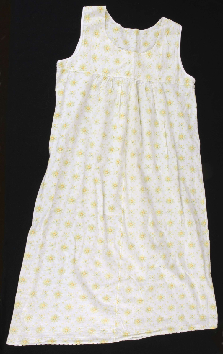 Lang ermeløs barnenattkjole med høyt liv. Hvit med gule og lysegrønne blomster.