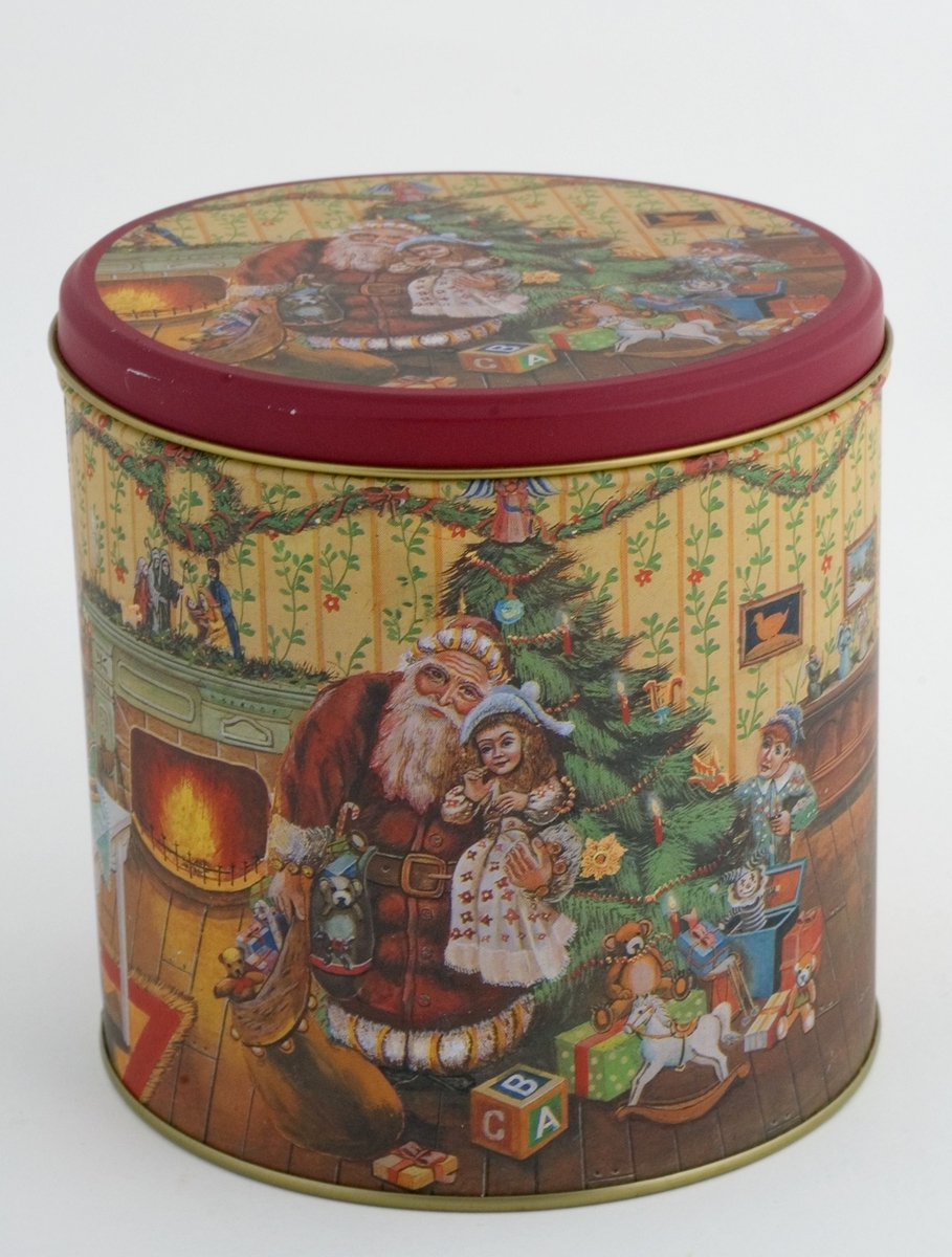 Sylinderformet kakeboks med lokk. Flerfarget julemotiv med juletre, julenisse, gaver m.m. på både lokk og boks. 