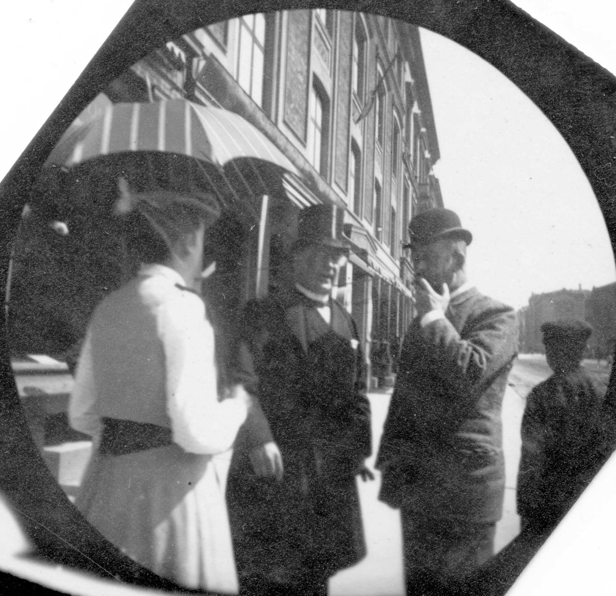 Professor Blytt, en mann og en kvinne prater på Karl Johans gate, Oslo. Stortinget skimtes i bakgrunnen.