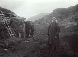 Kvinne i samisk drakt, Ellen, stående foran inngangen til ga