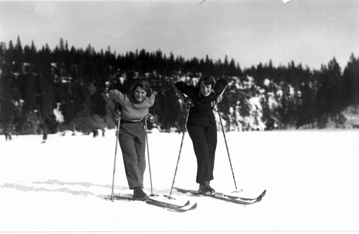 Slalåmrenn, Tryvannsåsen, Oslo. 1934. To kvinnelige skiløpere tar en hvilepause på Tryvann.