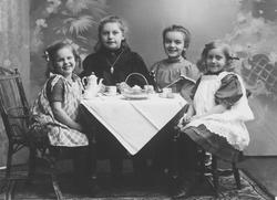 4 piker sitter rundt et dekket bord. Malt bakteppe med bregn