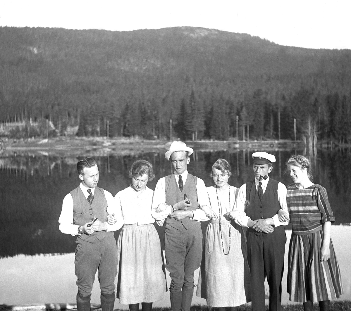 Seks unge mennesker stiller til fotografering før avreise fra feriested, antagelig ved Harestuvatnet. Fritjof Arentz nummer to fra høyre. Fotografert 1921.