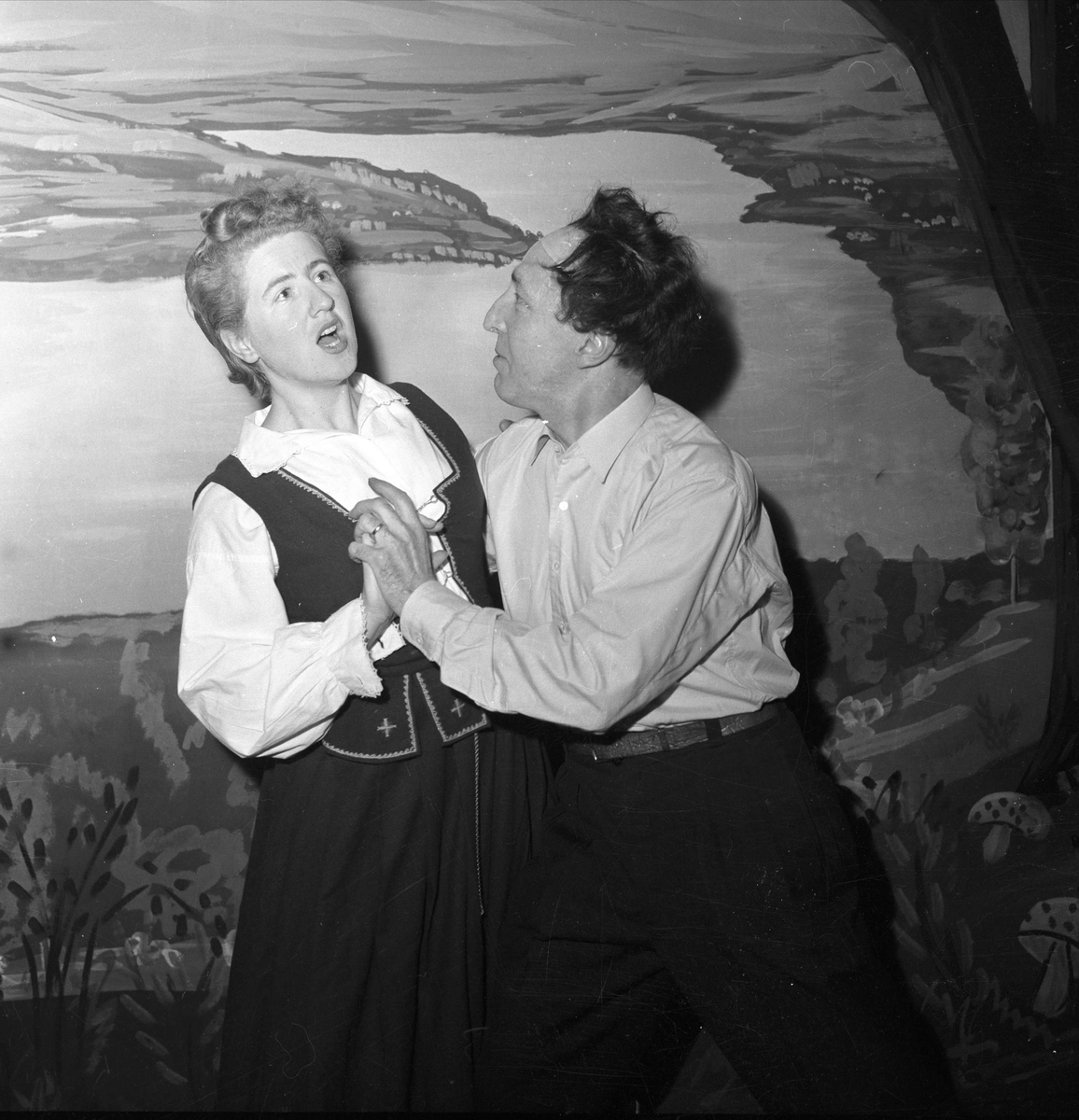 Par danser med kulisser i bakgrunnen 19.11.1954. Bygdelag.