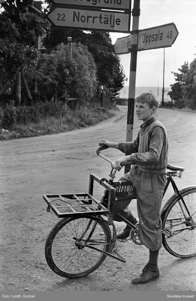 Pojke med paketcykel i vägkorsning. Rimbo, Uppland