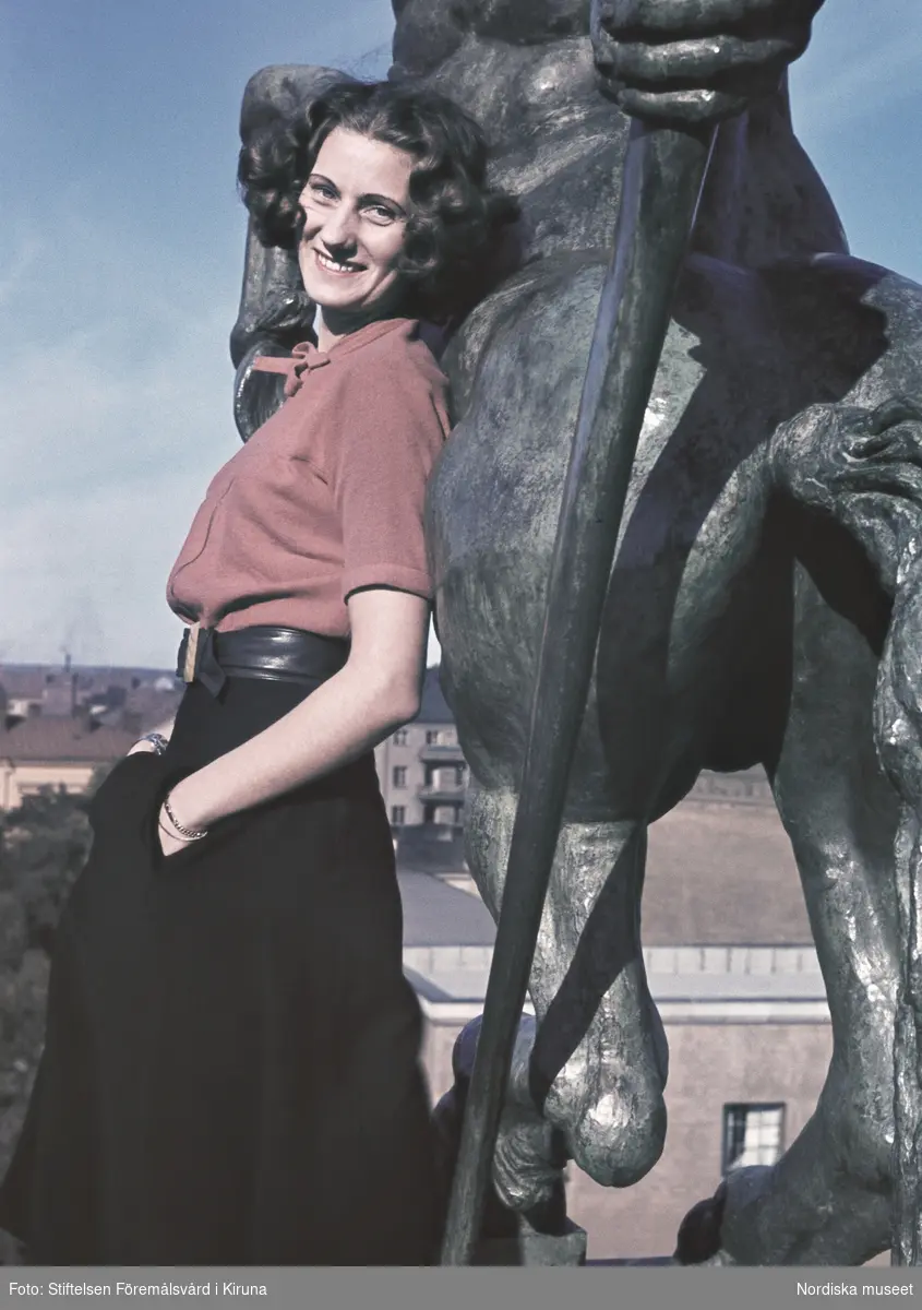 Kvinna iklädd röd blus och svart kjol. I bakgrunden Sigrid Frimans skulptur Kentauren från 1939 i Observatorielunden.