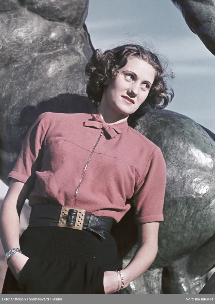 Kvinna iklädd röd blus. I bakgrunden Sigrid Frimans skulptur Kentauren från 1939 i Observatorielunden.