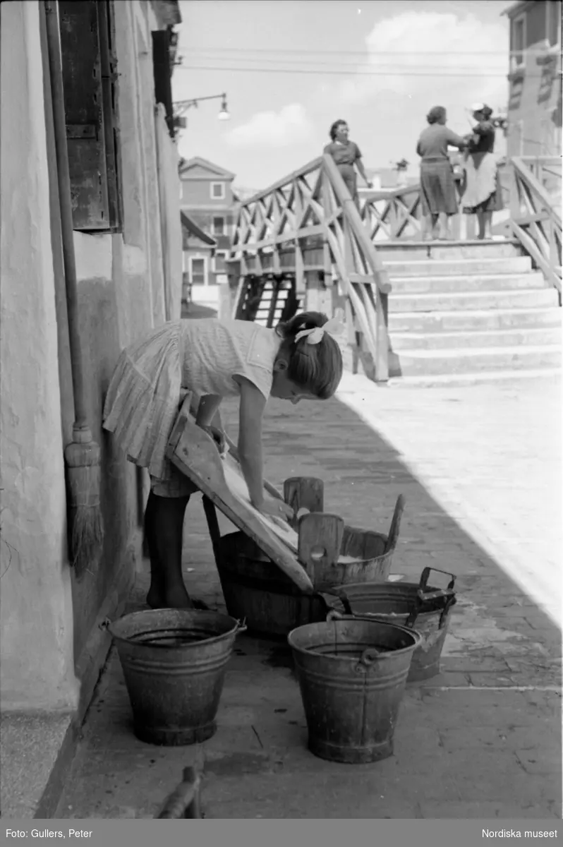 Flicka står på gatan och tvättar. Italien