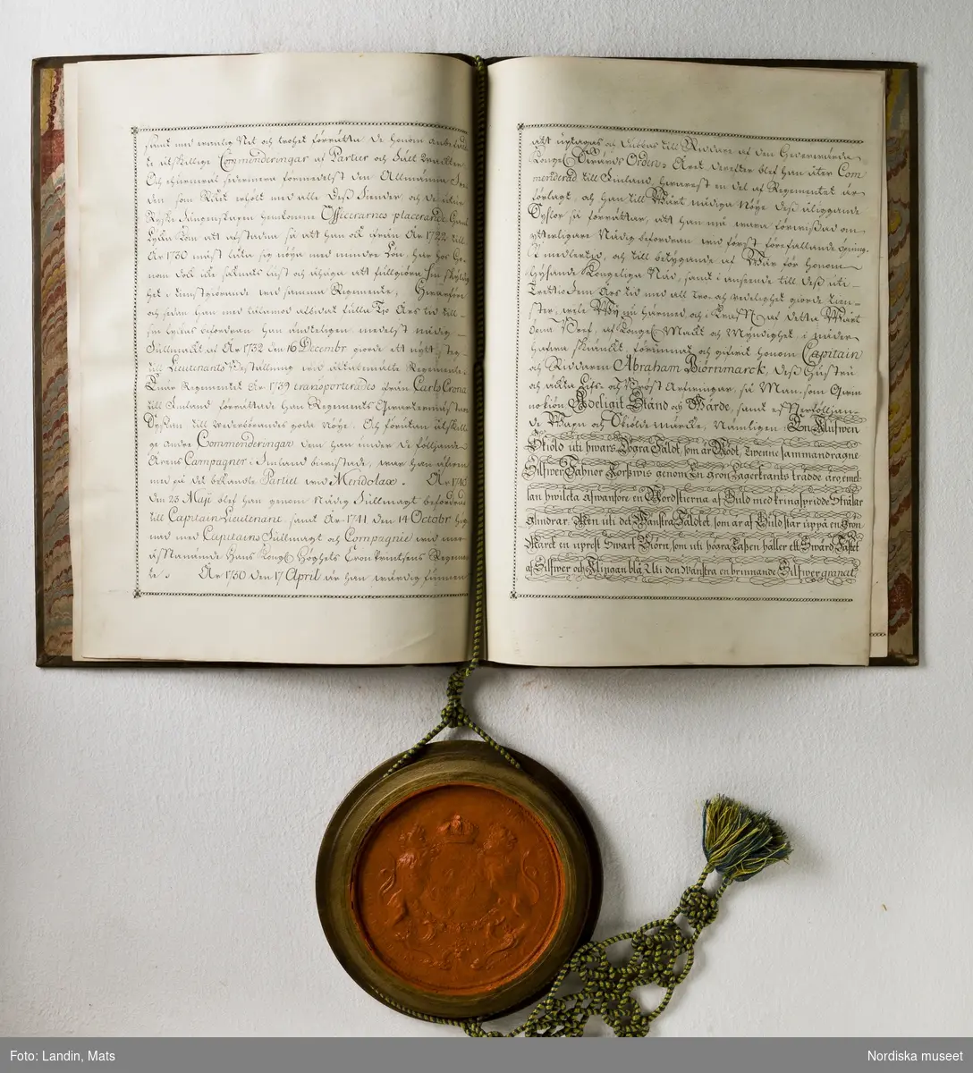 Adelsbrev för kapten Abraham von Björnmarck signerat 1751 av Adolf Fredrik. Sköldebrev. Fyra pergamentsblad, brunt skinnband med guldprägling. Sigill i träkapsel.