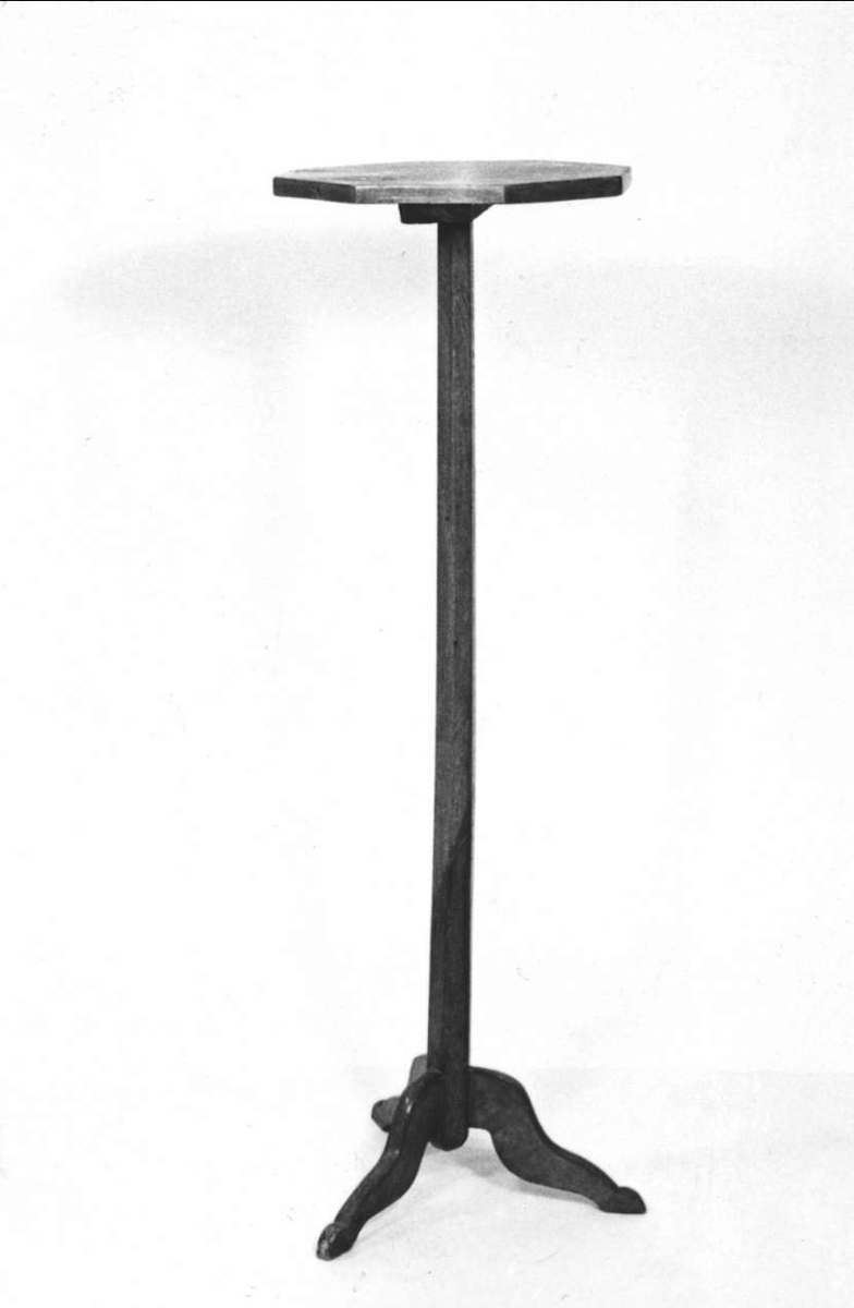 Piedestal av polerat trä, åttkantig skiva av masurbjörk, pelarben av ek, tre fötter.

