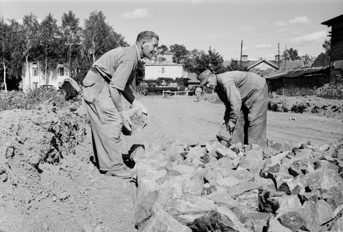 "Sommarrush för gatukontoret" - gatuarbetarna Axel Gustafsson och Eskil Andersson på Prästgårdsgatan, Stabby gärde, Uppsala juni 1952