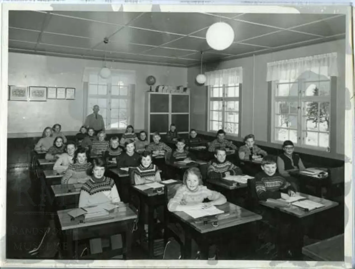 Skolebilde fra Nordre Oppdalen skole. Lærer og 24 elever sitter ved pulter i klasserom, 6. klasse
