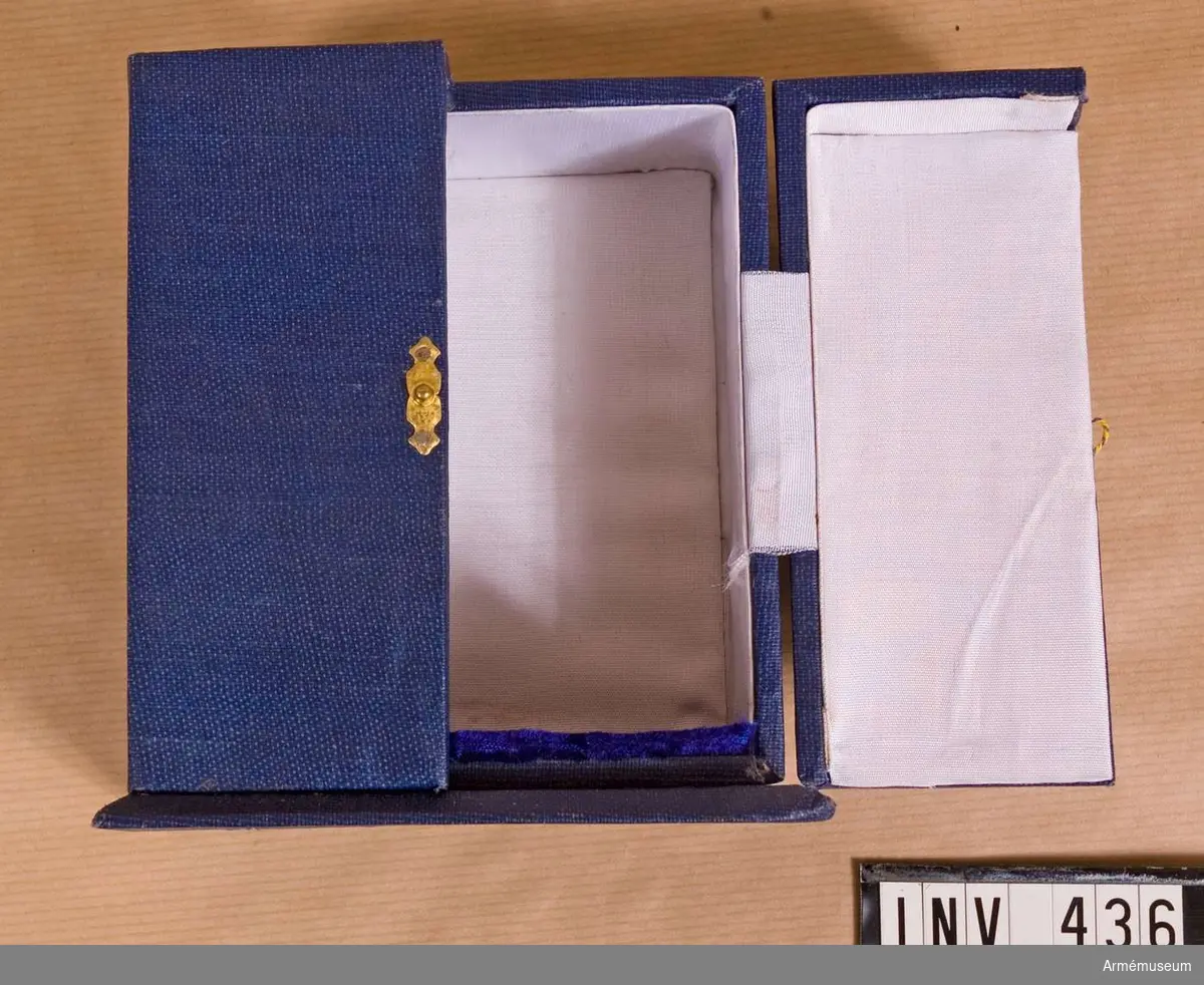 Samhörande nr är 294-299, 321-350, 400-448 (435-436).
Fodral t minnestecken.
Från ingenjörtruppskolan i Poona (Pune), Indien. Överlämnat 1975-01-25 under CA besök vid indiska arméni Poona ( jan 1975. "From Maj.Gen. K C Soni, AVSM, Commandant, Commandant, College of Military Engineering, Pune." Asken i blå klot är utformad som ett litet skåp med två dörrar, som låses på mitten med ett litet spänne. Invändigt klätt med vitt konstsiden och botten med blått sammet. Mått, botten: 115x85 mm, asken: 120x70 mm.
