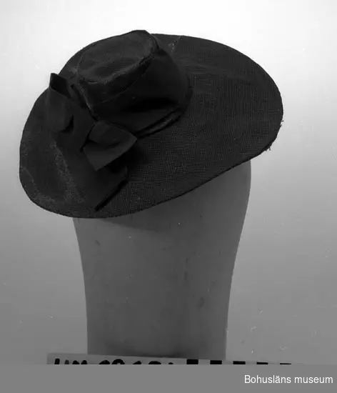 471 Tillverkningstid 1930-1940
410 Mått/Vikt ! BRÄTTB. 8 CM
394 Landskap BOHUSLÄN

Mörkblå liten hatt med miniatyrkulle och brätten. Nerdraget parti baktill.Taftfodrad.