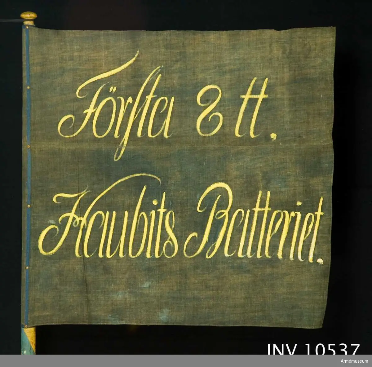 Grupp B.

Duk med inskrift: "Första 8 tt Haubits Batteriet". Svart med gul text.