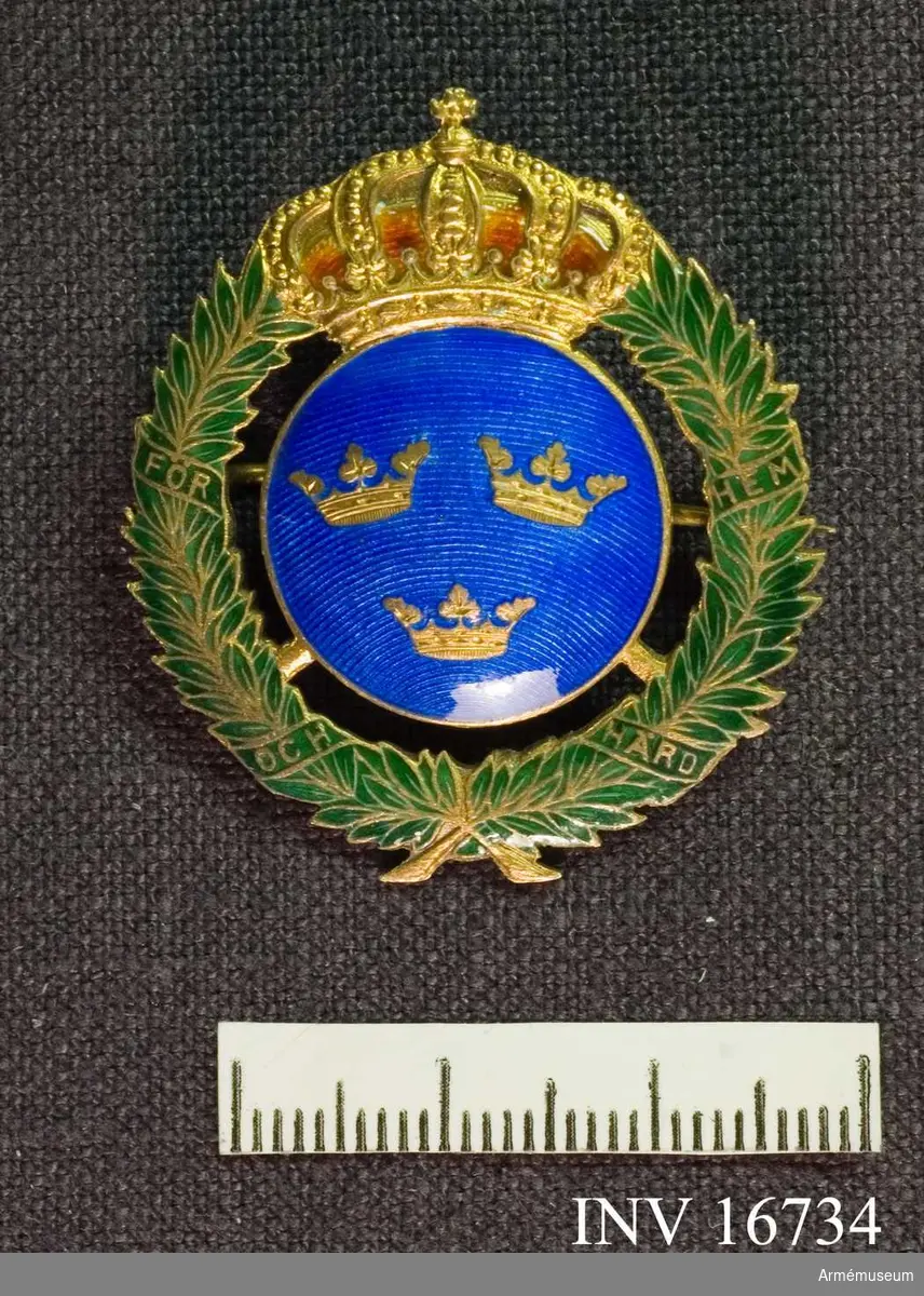 Medaljen visar det lilla riksvapnet med blå botten i emalj med  tre kronor krönt med kunglig krona med kudde av röd emalj. Omgärdat av en grönemaljerad lagerkrans på vars banderoll det står: För hem och härd. För övrigt är märket förgyllt. Förvaras i en liten platt rund svart ask.

Samhörande nr är AM.16734-16750