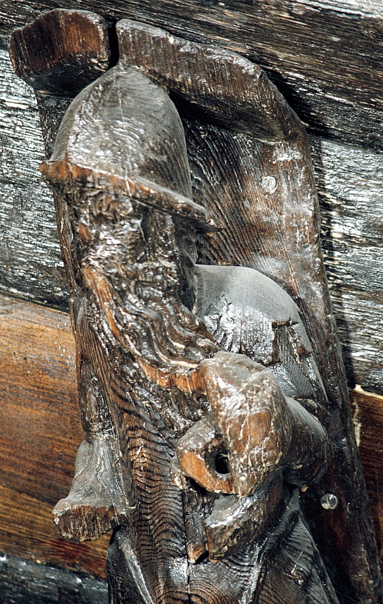 Krigare iklädd romersk rustning samt en osmyckad hjälm med breda, nedhängande hjässkydd. Mannen har långt, mot vänster draget skägg som tycks fladdra för vinden. Huvudet är vridet något åt höger. Rustningens nederdel utgörs av ett nedre och större lager rektangulära flikar över tunikan, delvis täckt av ett större och ett mindre lager av avrundade flikar. Höger hand saknas. Troligtvis har figuren hållit en fackla eller lampa i den nu saknade handen. Med vänster hand, som är skadad, håller figuren ett spiralvridet blåsinstrument, erinrande om ett valthorn. Instrumentet är skadat upptill har varit anslutet till mannens mun för att markera att han blåser i det.

Kroppstyngden vilar på höger ben medan vänster ben är böjt och fört något åt sidan. Sockeln, som är enkel och odekorerad, är avnött framtill.
Bortsett från ovannämnda defekter är skulpturen relativt välbevarad.

Text in English: Warrior clad in Roman armour, with long beard swept to the left, as though being blown in the wind. Head turned slightly to the right. The man wears an undecorated helmet with broad, hanging protective flaps. The right hand is missing but would probably have held a torch or lamp. The left hand is slightly damaged but holds a spiral-shaped wind instrument which is reminiscent of a hunting horn. The instrument is damaged but has been attached to the man''s mouth to show that he was blowing it. The weight of the body rests on the right foot, while the left leg is bent slightly and the foot is placed a little to the side. The base is simple and undecorated and rather worn in front.
Aside from the above-mentioned defects the sculpture is rather well preserved.