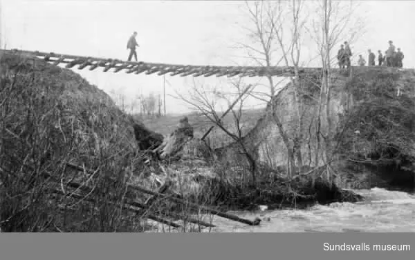 Statsbanan mellan Sundsvall-Ånge hänger fritt i luften sedan banvallen försvunnit i samband med vårflodens härjningar 1919. Fotot taget från Grönborgssidan.