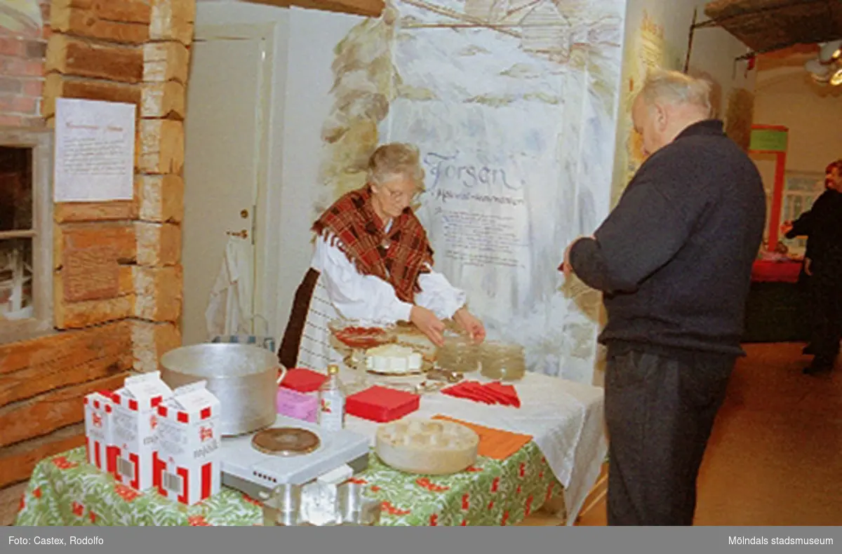 Julmarknad på Mölndals museum, 4 december 1994.
I Kållereddräkten Maj-Britt Björkman från Kållereds Hembygdsgille som säljer äggost till Bengt Wall från Krokslätt.