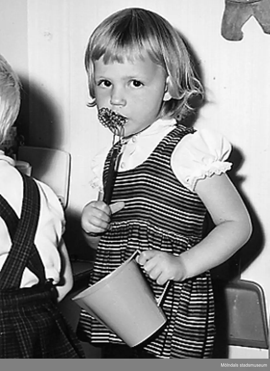 En flicka (Marita Björk, född Andersson) ståendes med en skål i ena handen och en visp i den andra. Holtermanska daghemmet 1953.