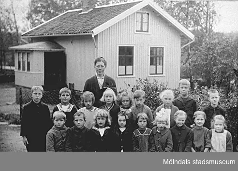 Ingrid Larssons skolklass utanför skolan i Livered, Kållered, 1920-talet. Småskollärarinna Hulda Holmén.