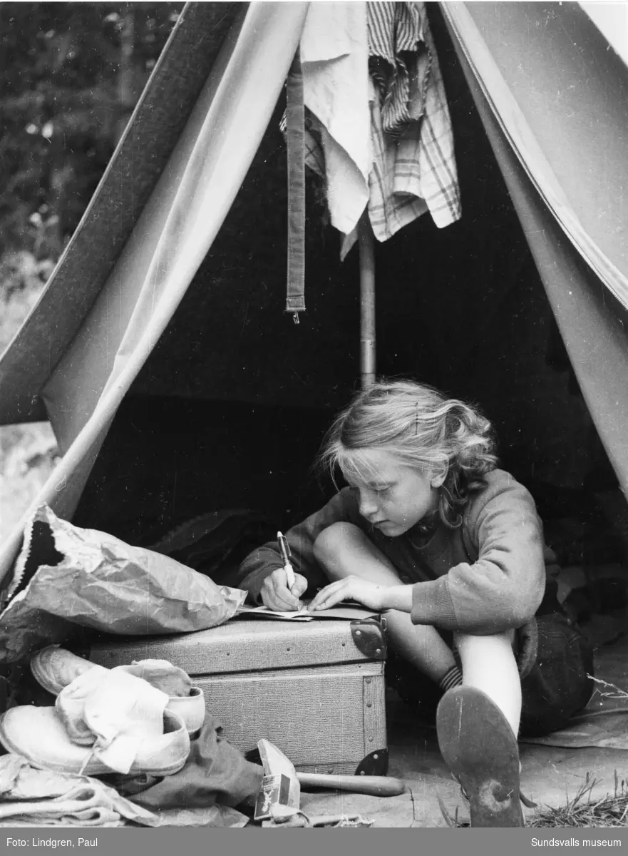 Flicka sitter i tält och skriver.
