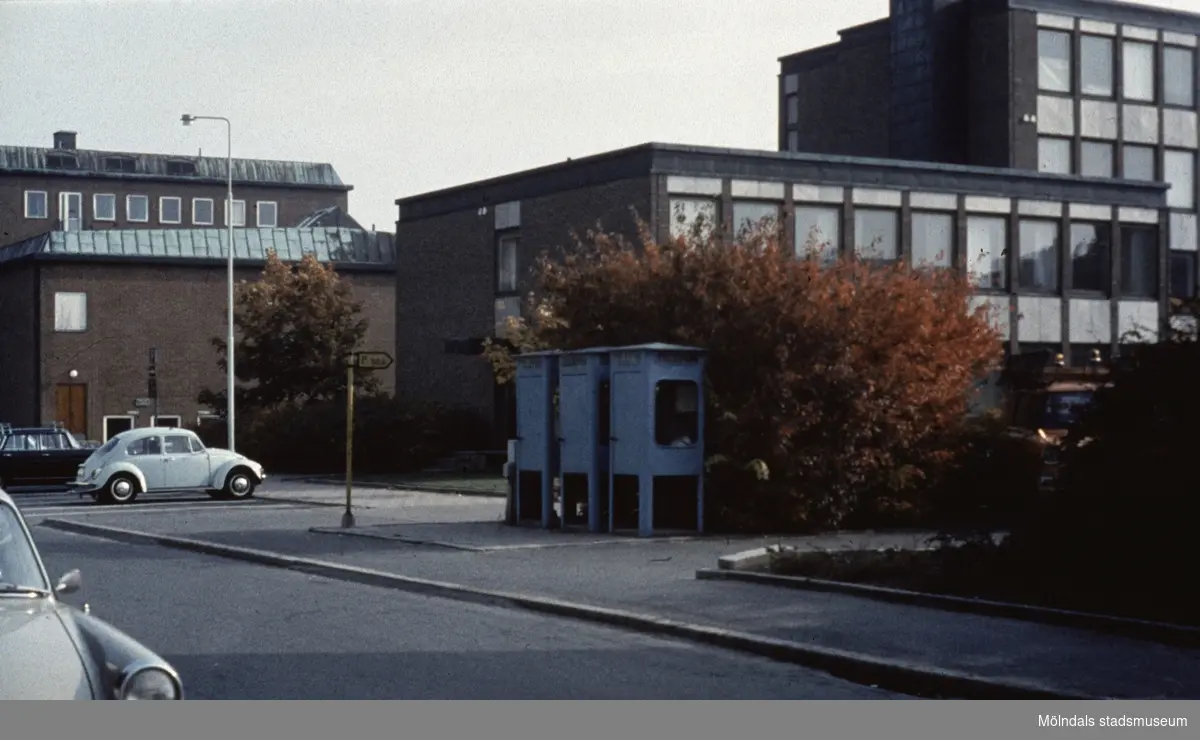 Vy från Knarrhögsgatan mot Folkets hus samt Stadshuset i Mölndal, 1970-tal. Till höger ses tre cyanfärgade telefonkiosker på trottoaren.