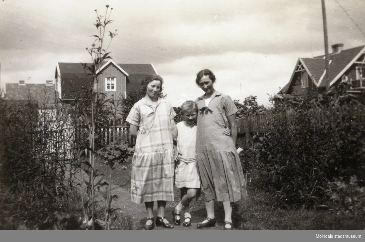 Elna Börjesson och Hilda Börjesson Hallgren fotograferade tillsammans med okänd kvinna i trädgården. Fotografi ur album som tillhört Hilda Börjesson Hallgren.