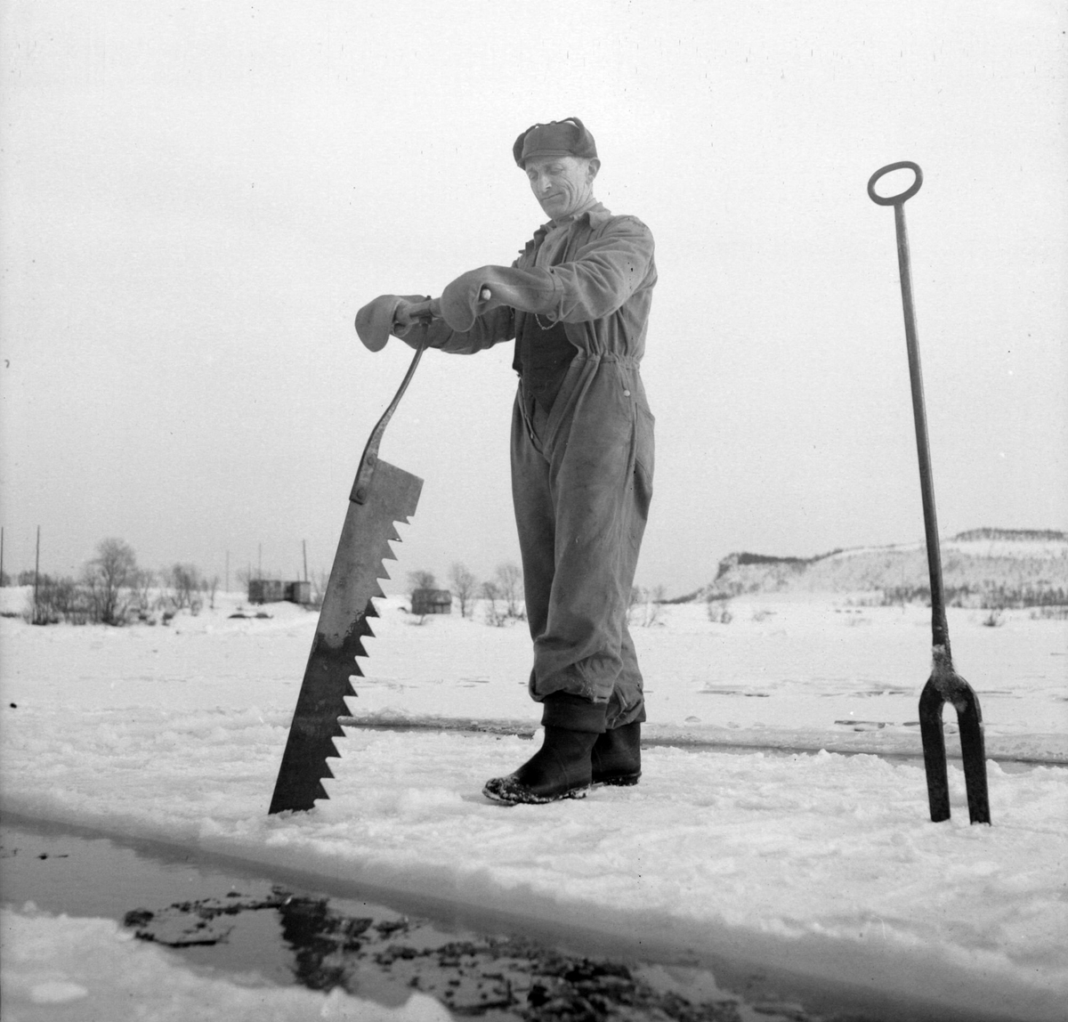 Isskjæring på Møkkelandsvannet, 1954. Mann arbeider med issag. Isen skulle brukes hos Bertheus Nilsen i byen.
