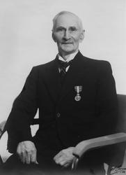 Studioportrett av Chr. Hannestad med Kongens fortjenestemeda