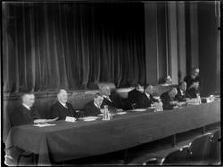 Gruppe menn sittende i panel bak langt bord.
Møte i Borrega