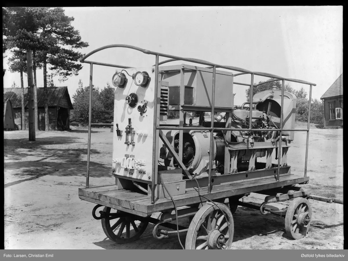 Aggregat fotografert på et gårdstun, hvor? ant 1942.

Tidilig versjon av mobilt reserveaggregat, også hestetrukket. Består av brenseltank, vanlig lastebilmotor (ser det ut som) og en lavspent generator.
Kontrolltavle av marmor med voltmeter og arbeidslys, spenningsregulator, hovebryter og sikringsavganger. Størrelse, kanskje 10-20 kW?