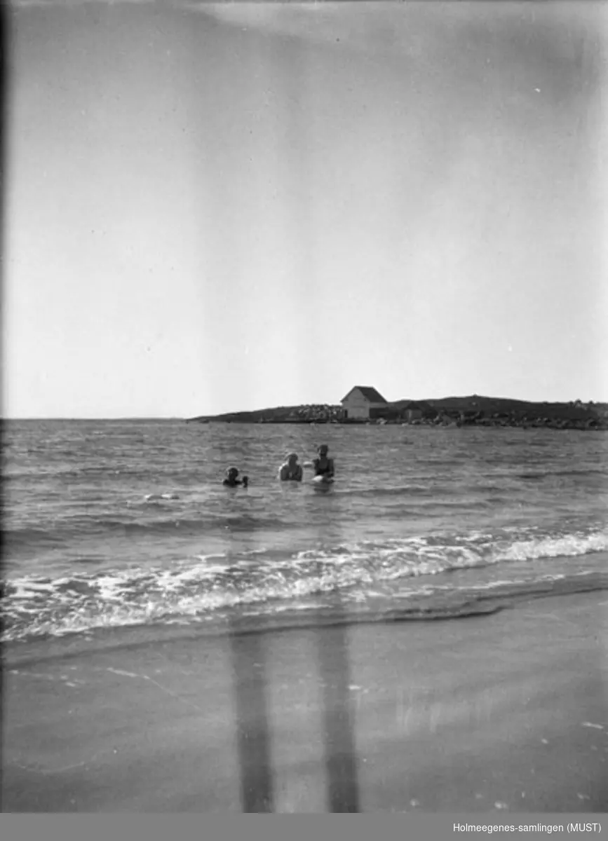 Tre kvinner med badehette og badedrakt bader like utenfor en strand (bare hode og skuldre stikker opp av vannet). Muligens samme sted og tidspunkt som ST.K.HE 2007-011-0056 til -0058.