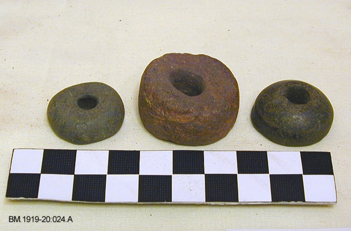 Fra protokollen: 3 spinnehjul av stein, det ene av rødaktig sandstein, skiveformet, som Jan Petersen: Vikingetidens redskaper, fig.166, med tverrmål 3,2 cm, og høyde 1,8 cm. De to andre er dannet av mer gråaktig sandstein, er mindre og har flate undersider og hvelvede oversider. Diameter 2,5 cm og 2,7 cm. Høyde henholdsvis 0,9 og 1,2 cm.