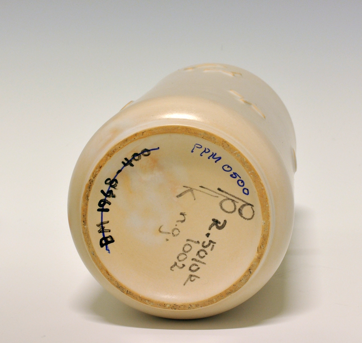 Vase av "keramikk". Sylinderform med inntrukket fotrand. På sidene stjerner, månedsigder og sirkler i relieff. "Lyserødbeige" glasur. 
Modell: R.5010k
Dekor: 1002