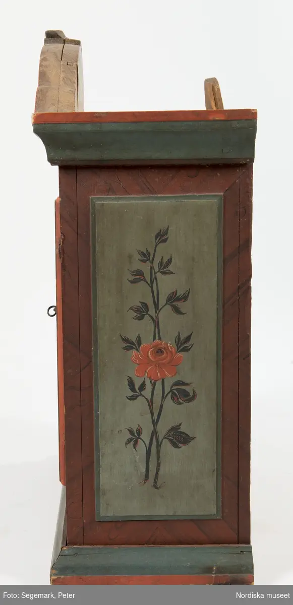 Katalogkort:
"av furu med 1 dörr, lås och nyckel, profil. fylln. med blommor i svart och rött mot grönt, röda och gröna lister, märkt: H. E. D. 1825."