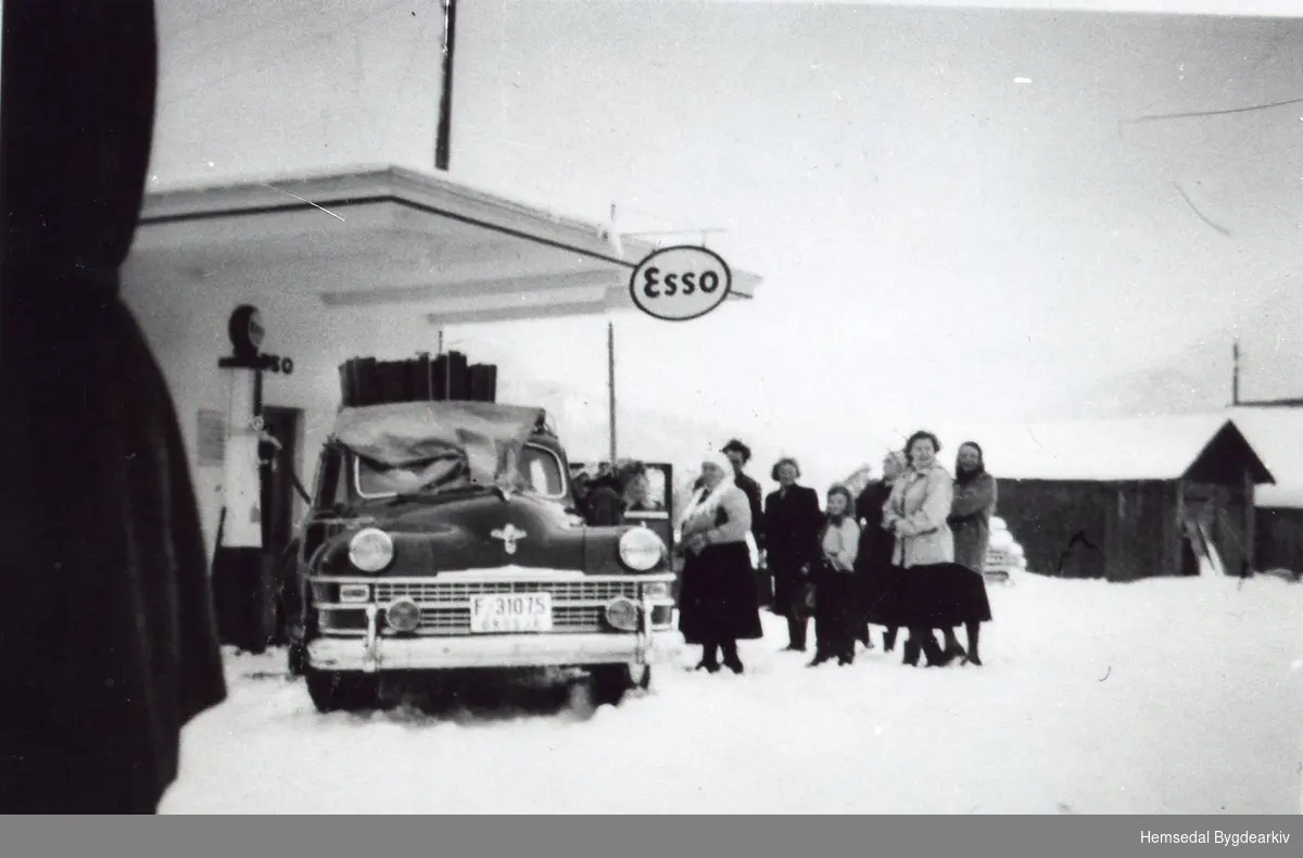 Drosje F-31075 , De Soto, til Mekkel Ødegård ved bensinstasjonen ved Tuv samvirkelag.
Frå venstre: Maria Fekene, jenta i midten er Ingebjørg Helgesen. Til høgre: Birgit Fekene.