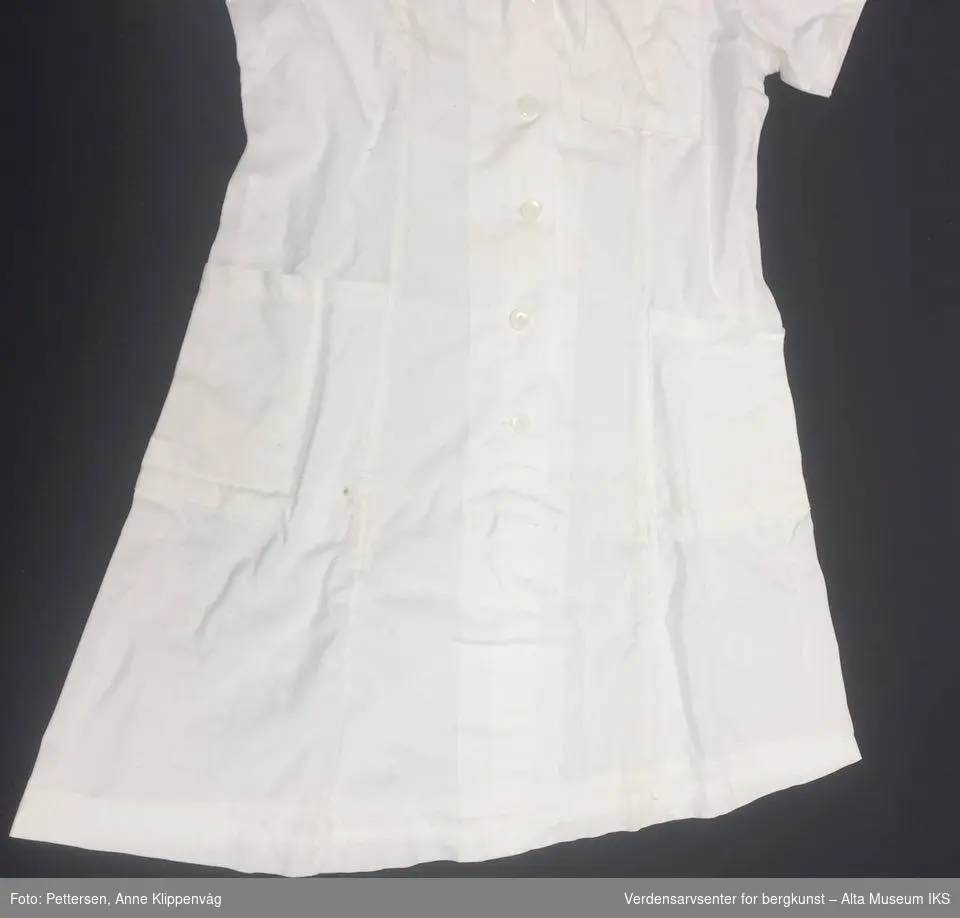 Hvit kortermet sykepleieruniform med seks hvite knapper i plast, og krage.