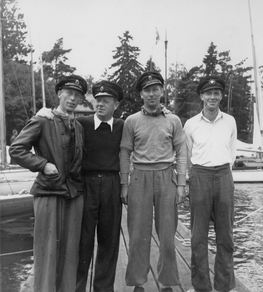 Besättningen på 30-S177 KORYBANT, som 23-24 juli 1942 vann The Marblehead Trophy under seglingar arrangerade av Stockholms Segel Sällskap. Bilden är tagen på sällskapets brygga vid Rastaholm vid Södra Björkfjärden. Fr v t h på bilden ses rorsman Oscar Plym, Conny Looft, Nils Nilsson och Alf Wallin.