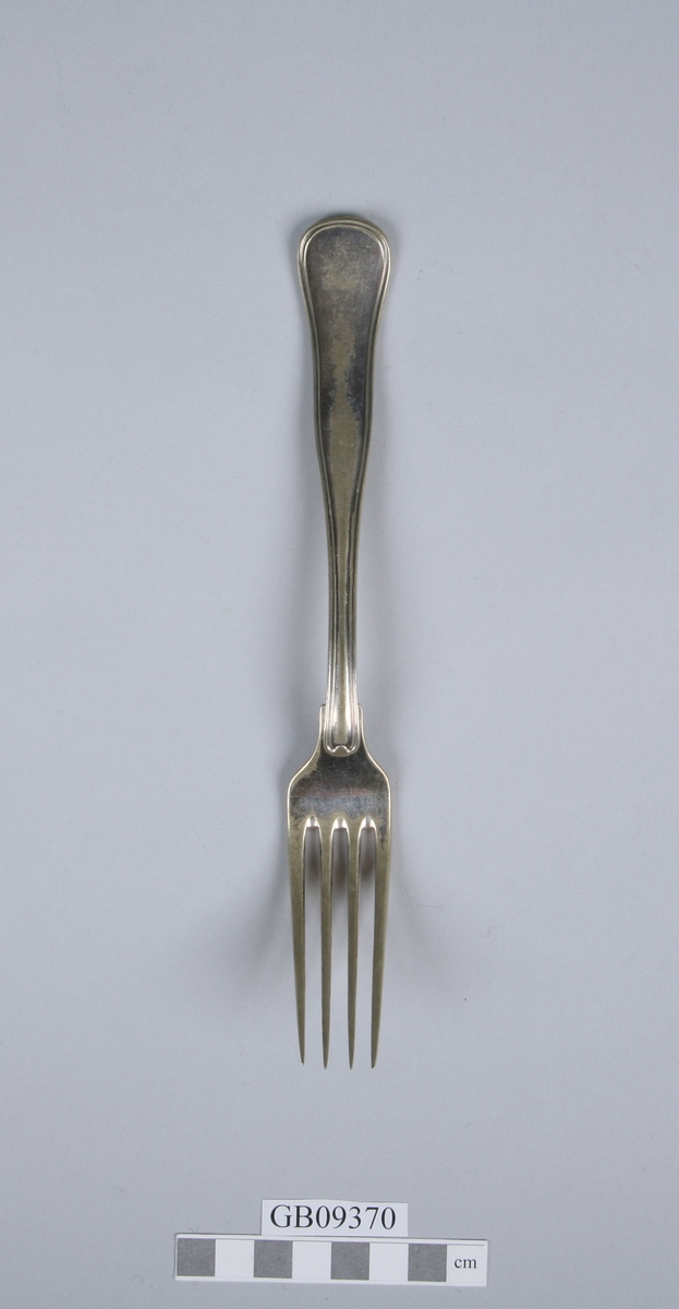 Stor gaffel med fire tinner. Dobbelkant rundt skaftet. 4 stempler på baksiden