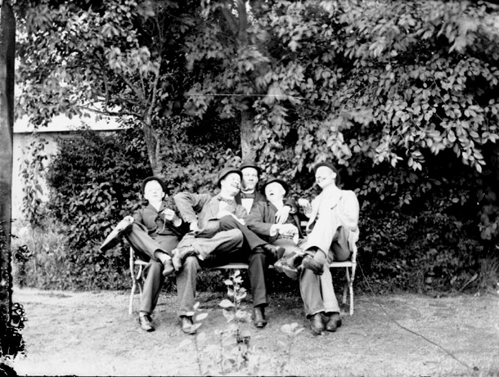 Fem unga män sittande på en bänk.
