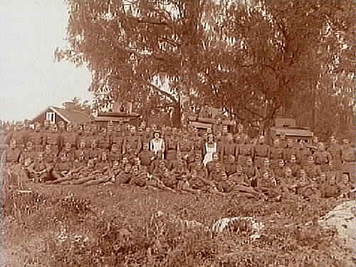 Inkallade soldater och två lottor vid I3 Regemente.
I bakgrunden två bepansrade kulsprutevagnar och en kanon.