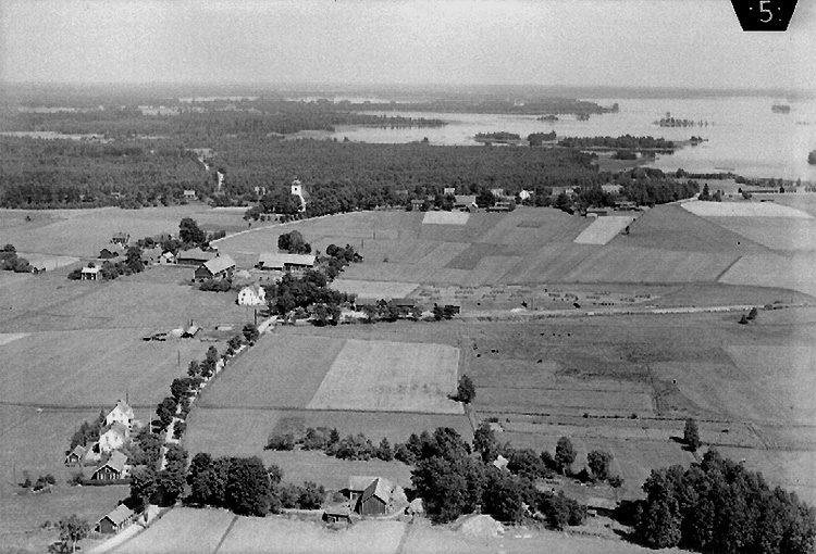 Flygfoto över Svennevad, kyrkan, bostadshus och byggnader, skogstrakten mot sjön Sottern.