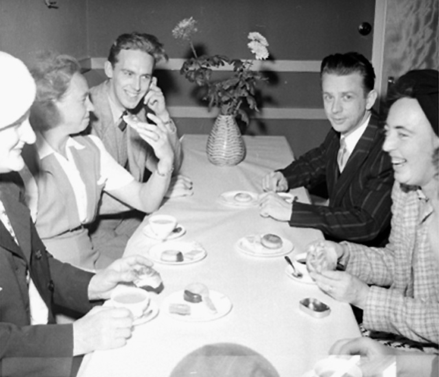 Kaffedrickande, grupp fem personer vid bordet.
Konsum