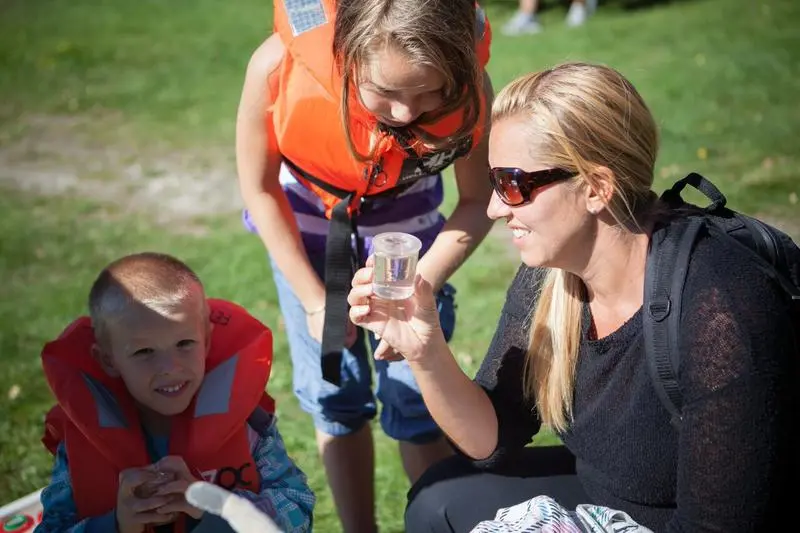 Foto av en familie som ser på et insekt i et vannglass