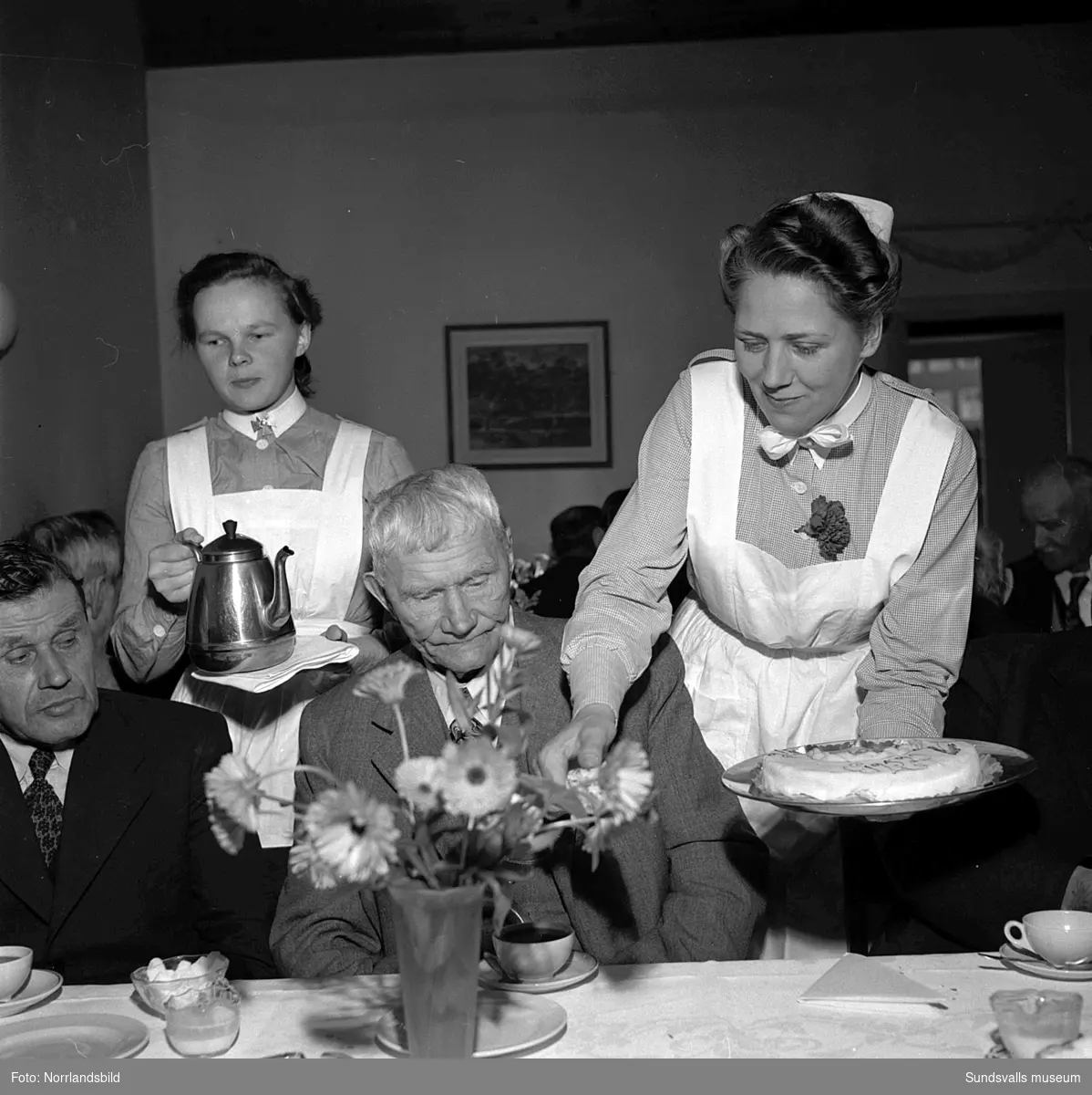 Lindgrens järnhandel firar 100-årsjubileum. Direktör Fridolf Brunnzell uppvaktar fru Palmqvist med en minnesskrift, samt kaffekalas på ett ålderdomshem.