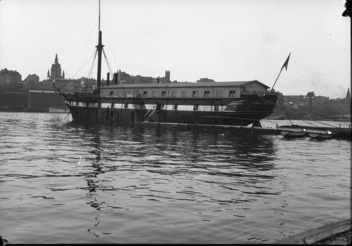 Före detta ångfregatten Vanadis och flottbron från Södra brobänken i Skeppsholmen.  Båten är byggd i Karlskrona 1862, längd 65m, bredd 12,5 , 14 kanoner. Världsomsegling 1883-1885. Ändrades till logementsfartyg 1904. Slopades 1941.